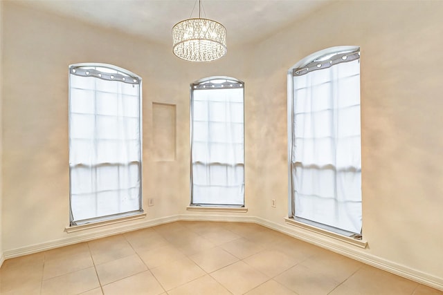 tiled empty room with an inviting chandelier