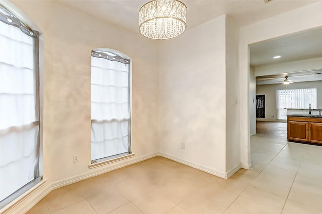 unfurnished room featuring ceiling fan with notable chandelier, sink, and light tile patterned floors