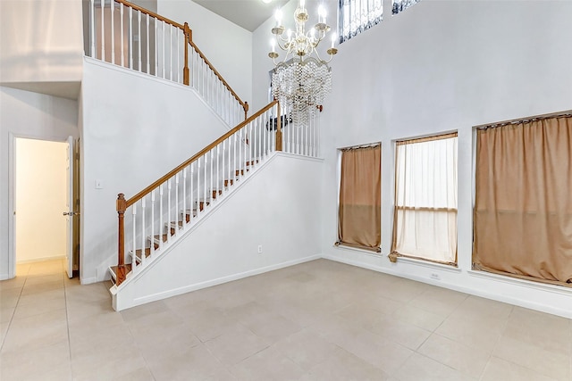 staircase featuring a towering ceiling, tile patterned floors, and a chandelier