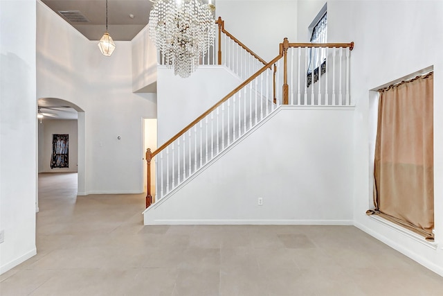 stairway featuring ceiling fan and a towering ceiling