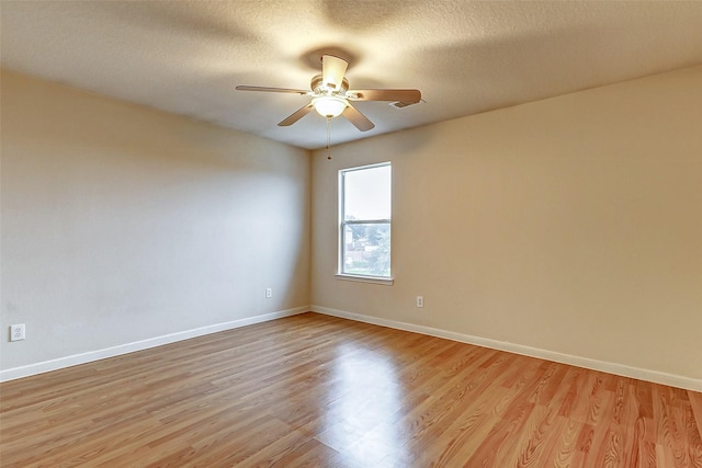 spare room featuring ceiling fan, light hardwood / wood-style flooring, and a textured ceiling