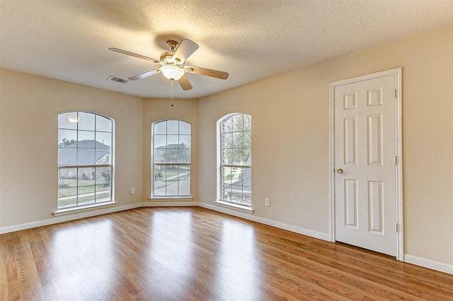 empty room featuring a textured ceiling, light hardwood / wood-style flooring, and ceiling fan