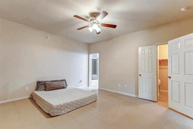 bedroom with ceiling fan, a spacious closet, light tile patterned floors, and ensuite bath