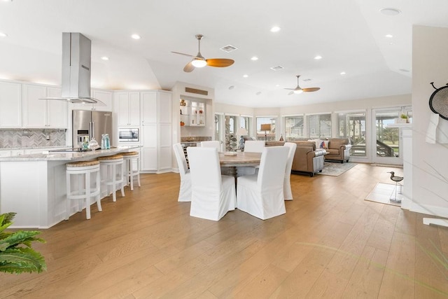 dining room featuring light wood-type flooring, lofted ceiling, and ceiling fan