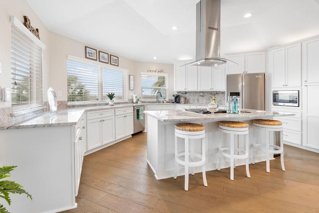 kitchen featuring white cabinets, island range hood, stainless steel appliances, and a kitchen island