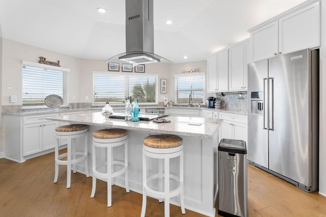 kitchen with a kitchen island, high end fridge, and white cabinetry