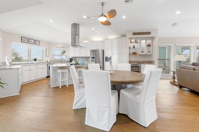 dining space with plenty of natural light, light hardwood / wood-style floors, vaulted ceiling, and wine cooler