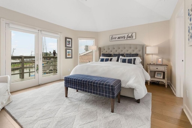 bedroom with hardwood / wood-style flooring, vaulted ceiling, and access to exterior