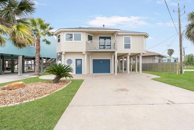 coastal home featuring a front yard, a garage, a balcony, and a carport