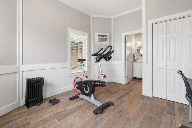 exercise room with ornamental molding, an AC wall unit, dark hardwood / wood-style floors, and radiator heating unit