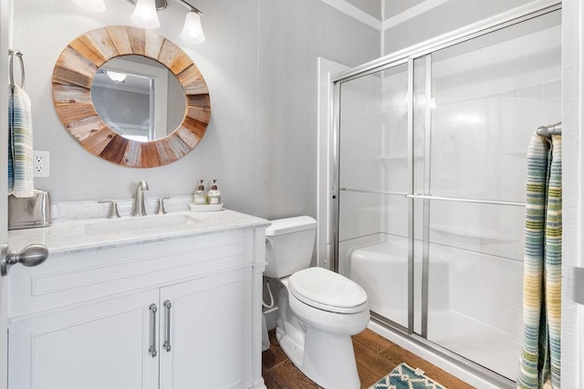 bathroom featuring toilet, hardwood / wood-style flooring, walk in shower, and vanity