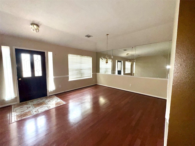 foyer with dark wood-type flooring and a notable chandelier