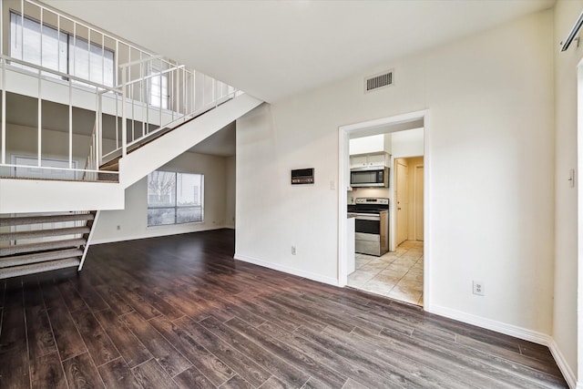 unfurnished living room featuring hardwood / wood-style floors and a high ceiling