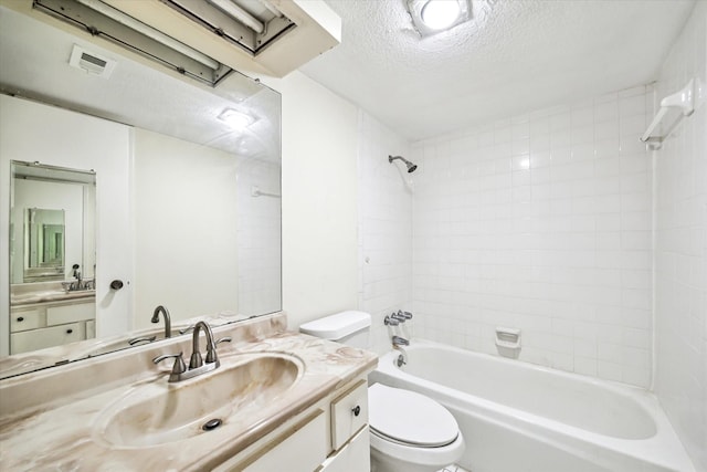 full bathroom with vanity, tiled shower / bath, toilet, and a textured ceiling