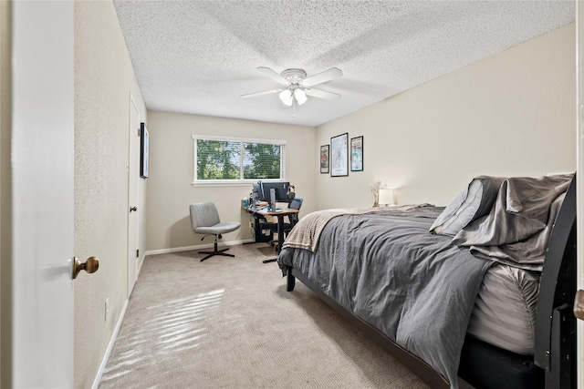 bedroom with ceiling fan, light colored carpet, and a textured ceiling