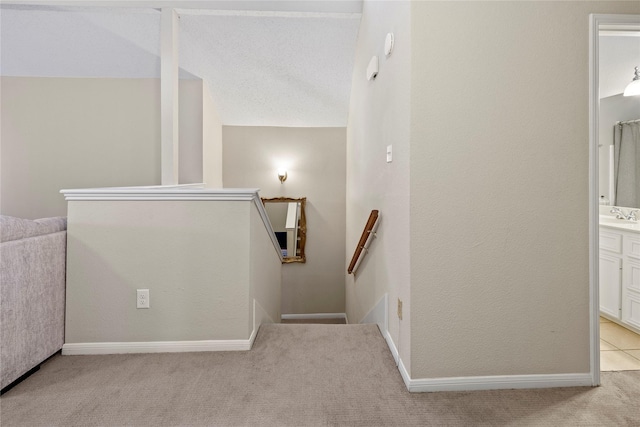 staircase featuring lofted ceiling, sink, and carpet floors