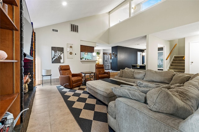 living room featuring a brick fireplace, light tile patterned floors, and high vaulted ceiling