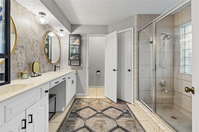 bathroom featuring vanity, a textured ceiling, a shower with door, and a healthy amount of sunlight