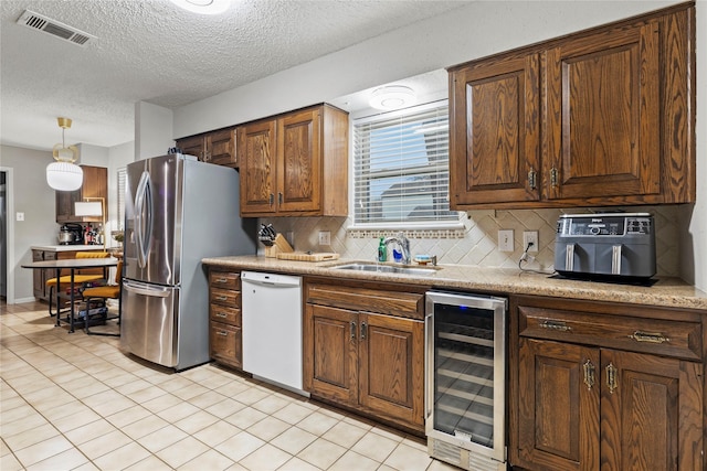 kitchen with sink, wine cooler, white dishwasher, stainless steel fridge with ice dispenser, and decorative light fixtures