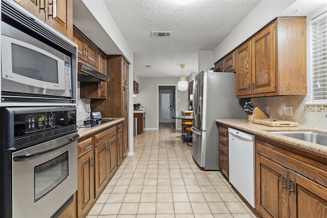 kitchen with light tile patterned flooring, sink, tasteful backsplash, a textured ceiling, and appliances with stainless steel finishes