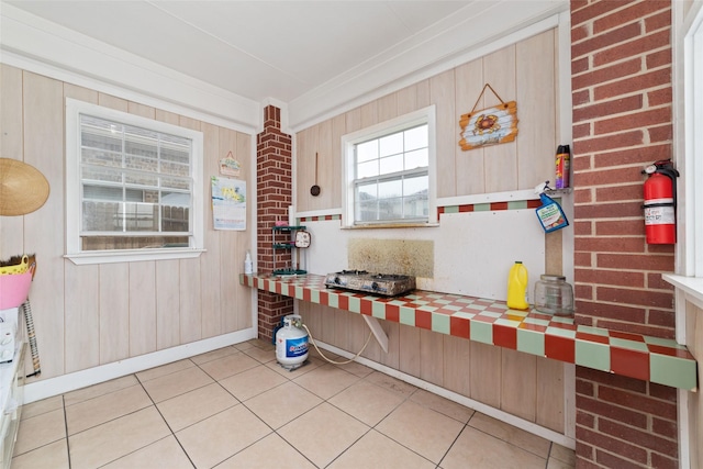 kitchen with light tile patterned floors, crown molding, and wood walls