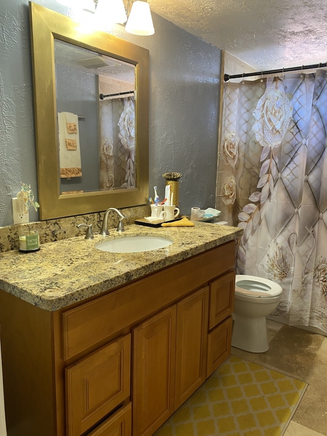 bathroom with vanity, toilet, and a textured ceiling