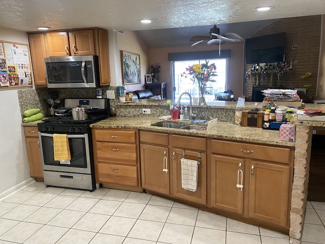 kitchen featuring appliances with stainless steel finishes, sink, light tile patterned floors, ceiling fan, and kitchen peninsula