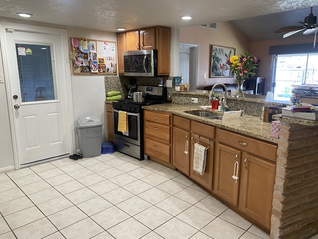 kitchen with tasteful backsplash, sink, light stone counters, kitchen peninsula, and stainless steel appliances