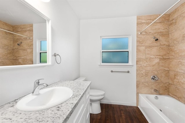 full bathroom with vanity, hardwood / wood-style floors, tiled shower / bath combo, and toilet