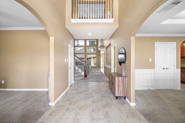 carpeted entrance foyer with crown molding and a high ceiling