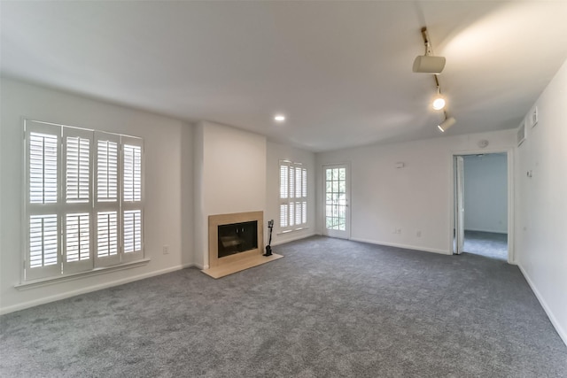 unfurnished living room featuring dark colored carpet and rail lighting