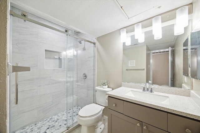 full bathroom featuring a stall shower, visible vents, toilet, a textured ceiling, and vanity