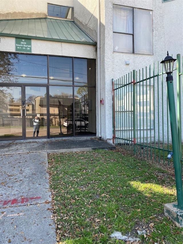 entrance to property featuring fence and stucco siding