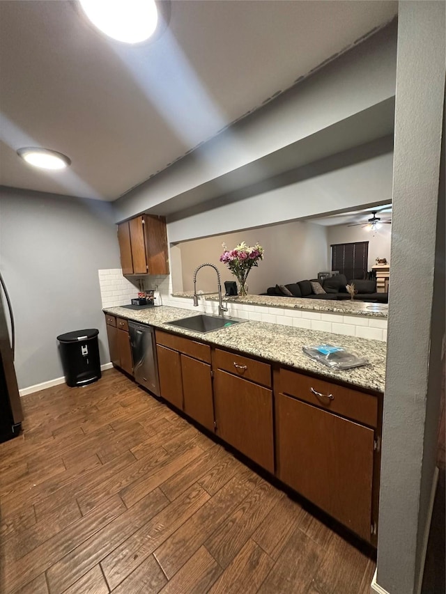 kitchen with decorative backsplash, dark wood-type flooring, open floor plan, a sink, and dishwasher