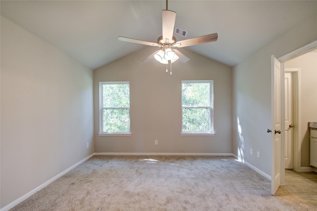 empty room with vaulted ceiling, plenty of natural light, light colored carpet, and ceiling fan