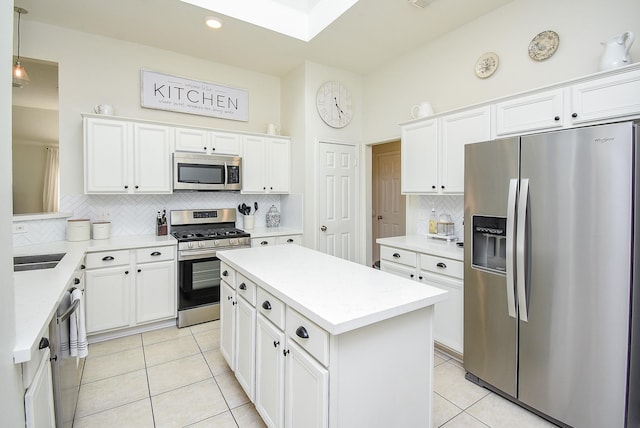 kitchen with light tile patterned floors, stainless steel appliances, a kitchen island, white cabinetry, and tasteful backsplash