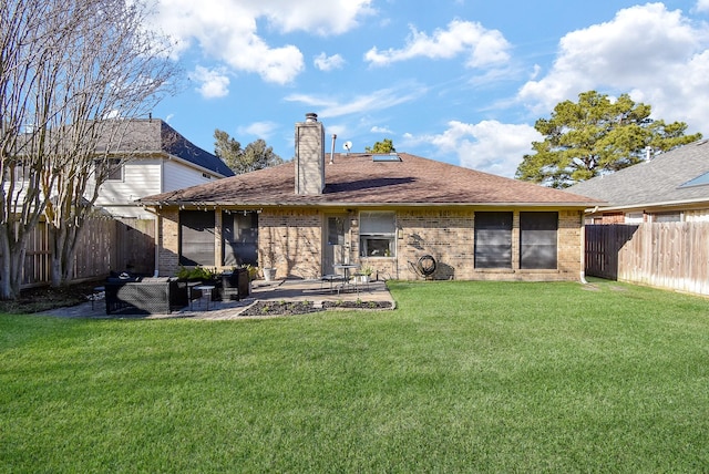 rear view of property with a fenced backyard, a chimney, a yard, a patio area, and brick siding