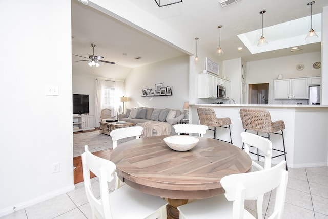 dining room with light tile patterned floors, baseboards, visible vents, a ceiling fan, and lofted ceiling