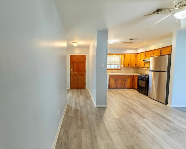 kitchen featuring black gas range, sink, stainless steel fridge, and light wood-type flooring