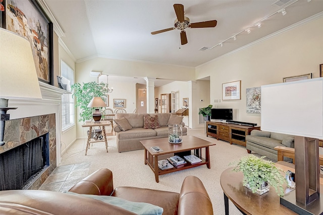 living room featuring decorative columns, a tiled fireplace, ceiling fan, crown molding, and carpet flooring