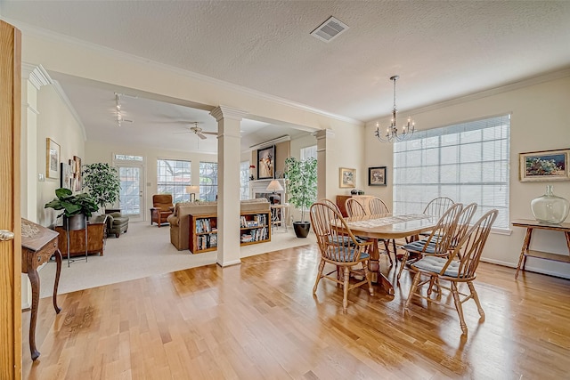 dining space featuring decorative columns, light wood-style flooring, and crown molding