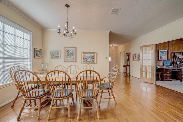 dining space with light wood-style floors, visible vents, crown molding, and a textured ceiling