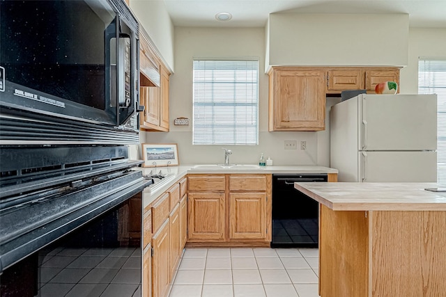 kitchen featuring light countertops, a sink, black appliances, and light tile patterned floors