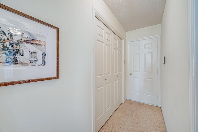 hall featuring light colored carpet and a textured ceiling