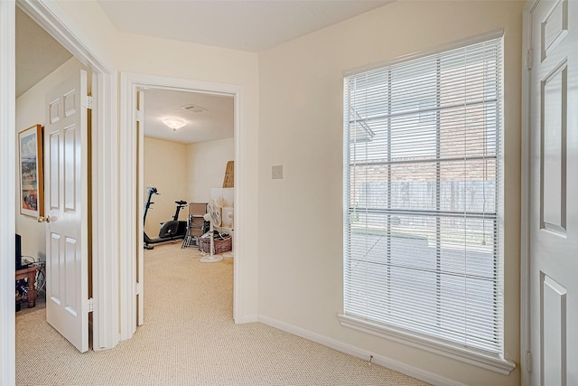 corridor featuring baseboards and light colored carpet