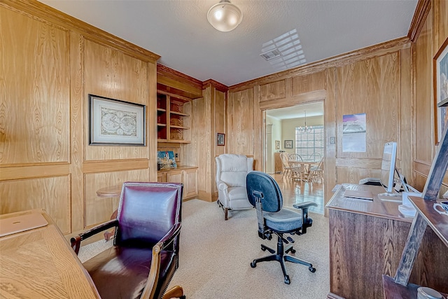 carpeted home office with ornamental molding, built in shelves, and wood walls