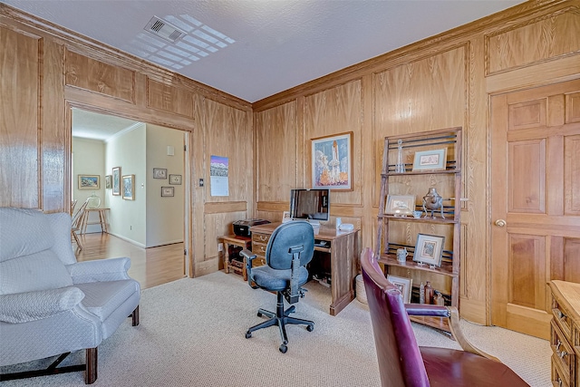 office area featuring light carpet, wood walls, visible vents, and crown molding