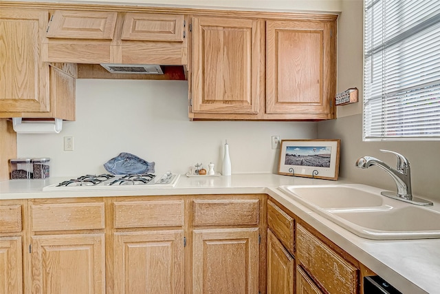 kitchen featuring white gas cooktop, light brown cabinets, light countertops, and a sink