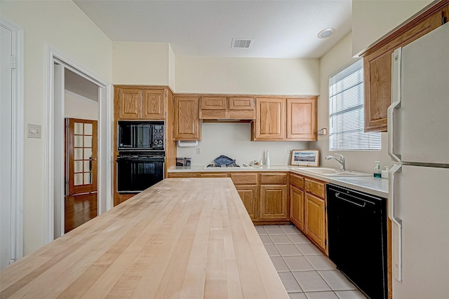 kitchen with visible vents, wooden counters, light tile patterned flooring, a sink, and black appliances