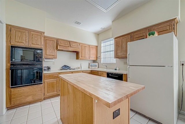 kitchen featuring light tile patterned floors, butcher block counters, a kitchen island, black appliances, and a sink